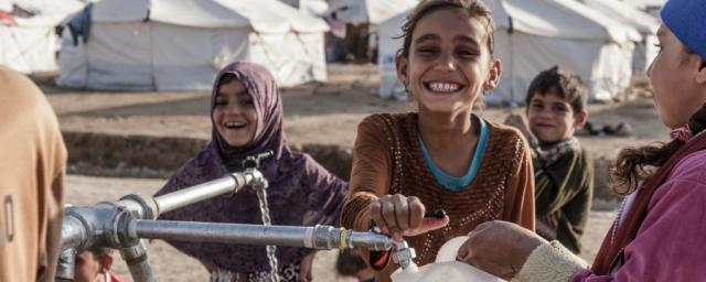 Children fill bottled with clean water at an Oxfam tap stand in Hassansham camp around 50km east of Mosul, Iraq. Credit: Tegid Cartwright/Oxfam Children fill bottled with clean water at a tap stand in Hassansham camp in east of Mosul, Iraq. Credit: Tegid Cartwright/Oxfam