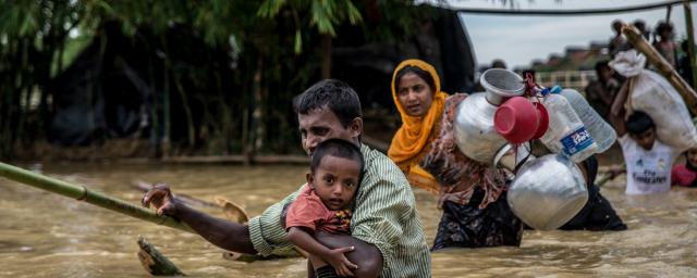 A father carries his son across a broken bridge on the edge of Balhukali camp, Bangladesh. Heavy rains flooded the areas where people had set up temporary shelters, forcing them to move to higher ground. Photo: Aurélie Marrier d’Unienville A father carries his son across a broken bridge on the edge of Balhukali camp, Bangladesh. Heavy rains flooded the areas where people had set up temporary shelters, forcing them to move to higher ground. Photo: Aurélie Marrier d’Unienville